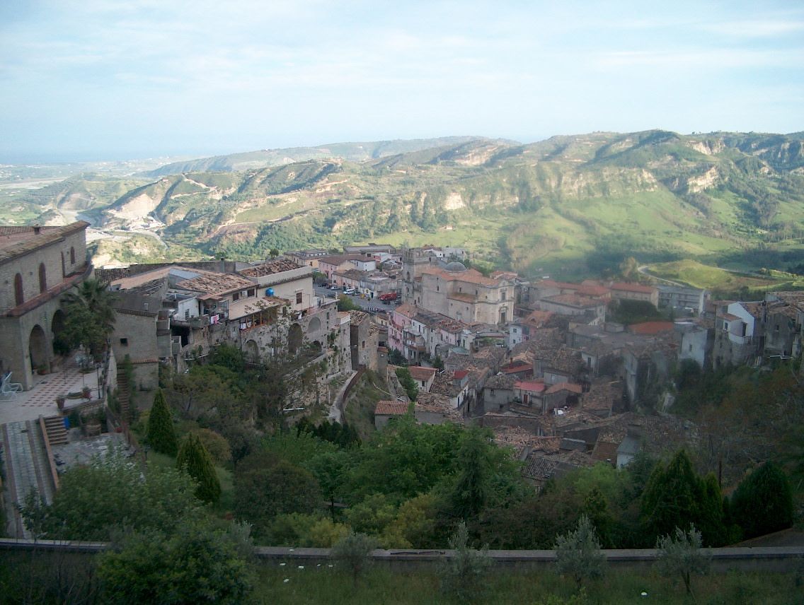 A hillside village in a small valley in Calabria, southern Italy, with tiled roofs and green slopes.