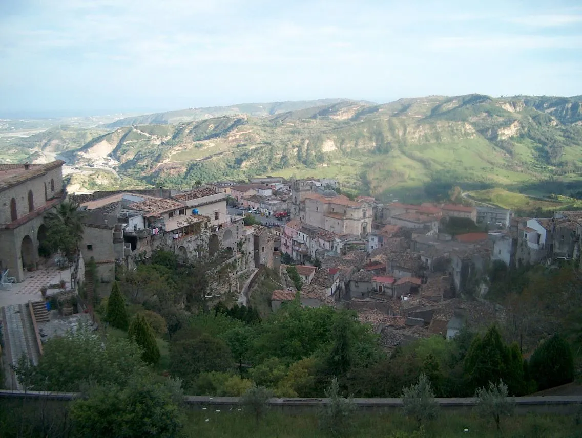 A hillside village in a small valley in Calabria, southern Italy, with tiled roofs and green slopes.