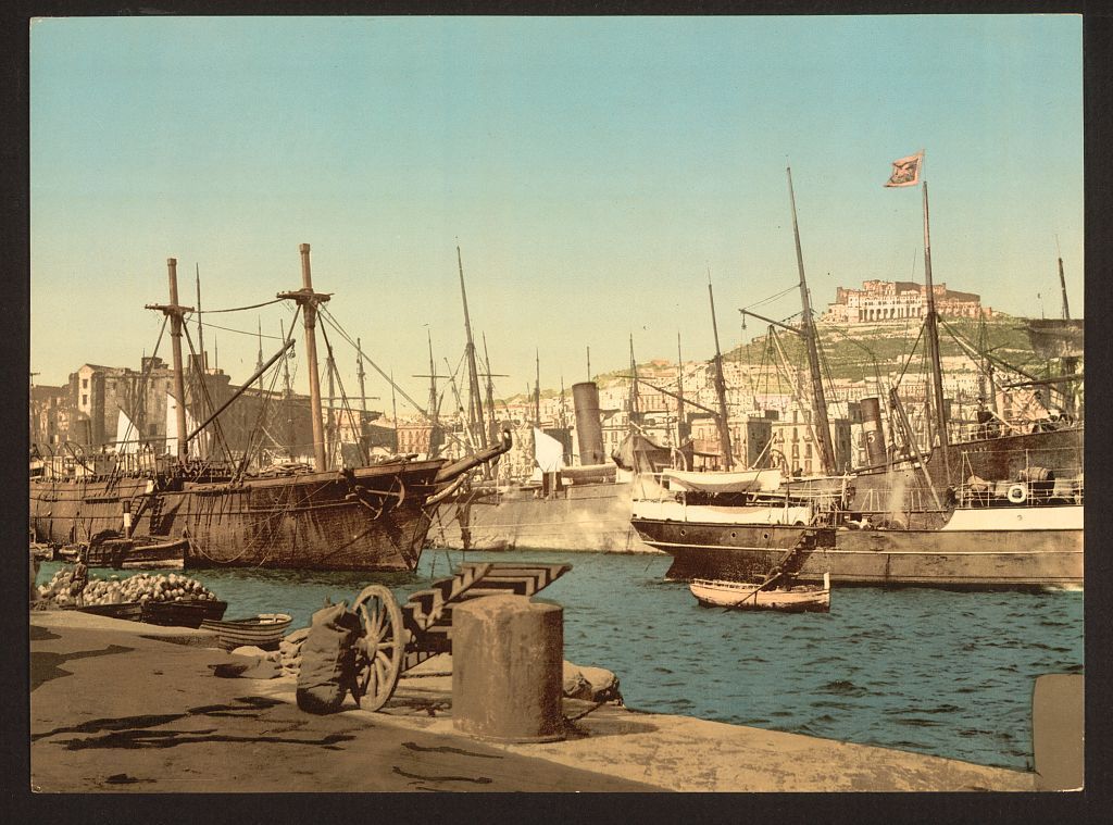 Historic photograph of the harbor at Naples, Italy, with ships along the waterfront.